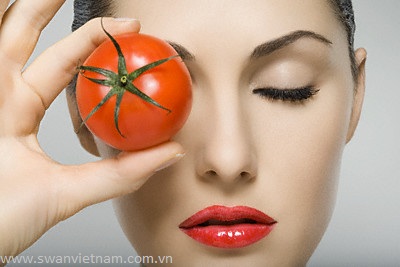 Woman holding tomato to her eye --- Image by © Image Source/Corbis
